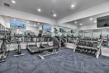 a gym with cardio equipment and televisions in a building